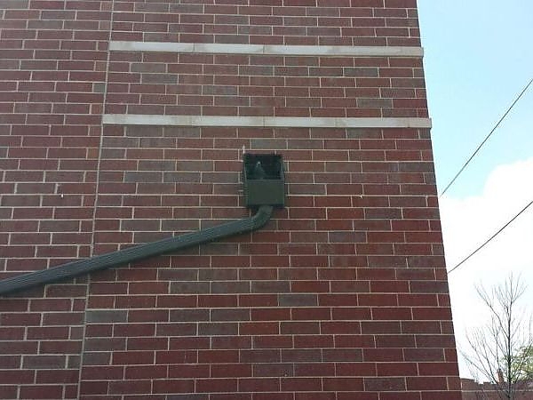 A pipe coming out of a brick building in a pest-free area